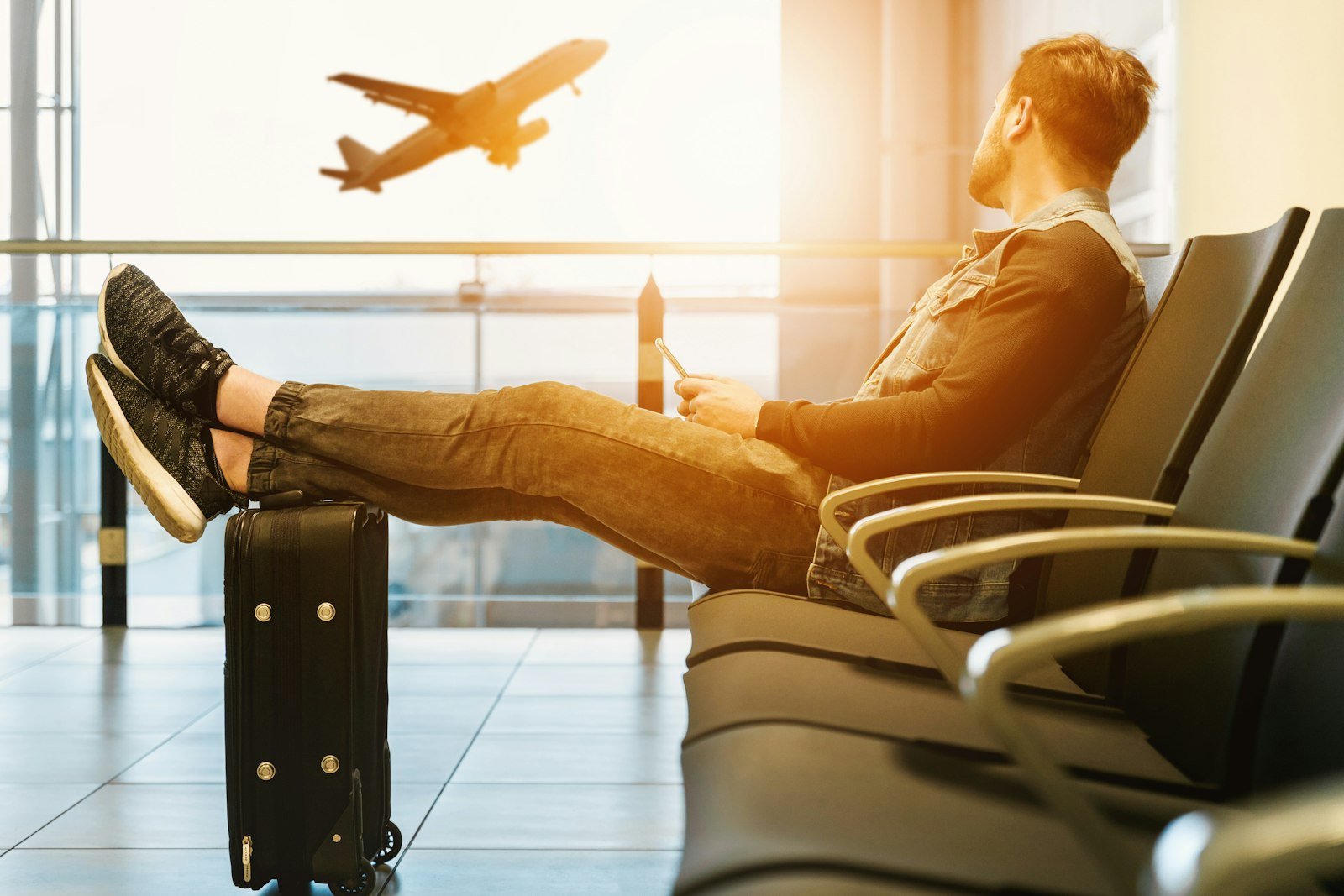 Traveler sitting in an airport waiting area with luggage