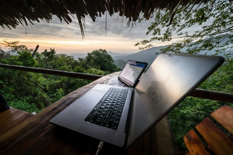 Laptop and phone on a wooden table with mountain view