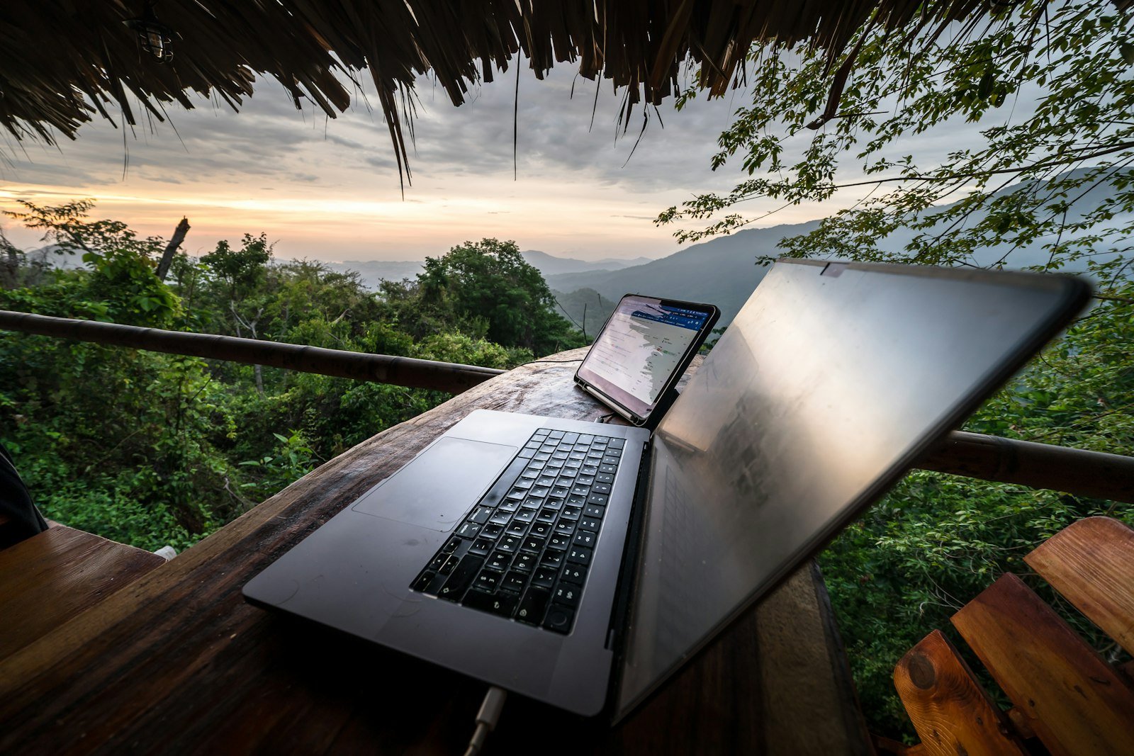 Laptop and phone on a wooden table with mountain view